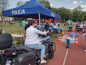 Zdjęcie kolorowe. Kobieta siedząca za kierownicą policyjnego motocyklu