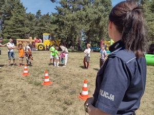 Zdjęcie kolorowe. Policjantka przygląda się zmaganiom dzieci w alkogooglach