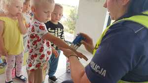 Zdjęcie kolorowe. Policjantka przybija dzieciom na rączce pieczątki