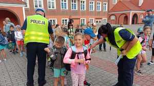 Zdjęcie kolorowe. Policjanci pod szkołą rozdają elementy odblaskowe