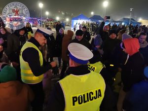 Zdjęcie kolorowe. Policjanci rozdają elementy odblaskowe