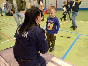 Zdjęcie kolorowe. Policjantka na macie z przejściem dla pieszych ćwiczy z dziećmi