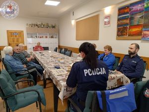 Zdjęcie kolorowe. Policjanci wspólnie z seniorami zasiadają przy wspólnym stole