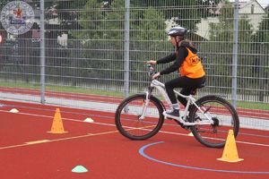 Zdjęcie kolorowe. Uczeń na rowerze podczas egzaminu