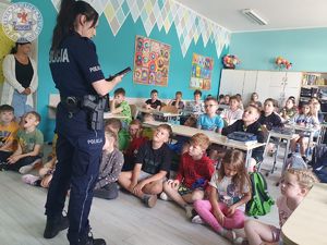 Zdjęcie kolorowe. Policjantka podczas spotkania z uczniami w szkolnej klasie