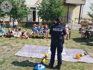 Zdjęcie kolorowe. Policjanci na terenach zielonych przy szkole prowadzą spotkanie z uczniami