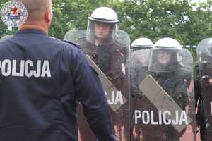 Zdjęcia kolorowe. Ćwiczenia z tworzenia szyków i ugrupowań w pododdziały prowadzone przez policjanta z umundurowanymi uczniami