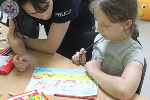 Zdjęcie kolorowe. Dzieci wspólnie z policjantkami rysują prace na konkurs Bezpieczne wakacje