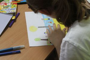 Zdjęcie kolorowe. Dziecko rysuje swoją prace plastyczną