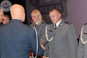 Zdjęcie kolorowe. Policjanci otrzymują akty mianowania na wyższe stopnie służbowe