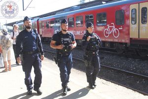 Zdjęcie kolorowe. Trzyosobowy patrol policji patroluje perony