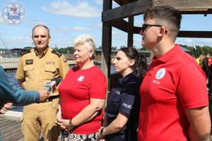 Zdjęcie kolorowe. Strażak, promotor zdrowia, policjantka, ratownik udzielają wywiadu mediom