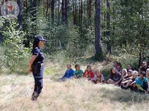 Zdjęcie kolorowe. Policjantka rozmawia z harcerzami