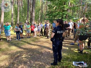 Zdjęcie kolorowe. Policjantka rozmawia z harcerzami