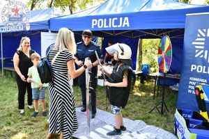 Zdjęcie kolorowe. policjantka zakłada dziecku tzw. &quot;żółwia&quot;