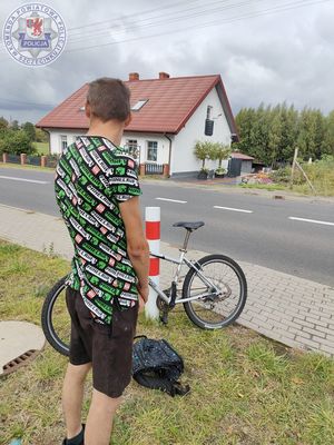 Zdjęcie kolorowe. Mężczyzna stoi obok roweru