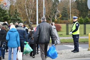 Zdjęcie kolorowe. Policjant ruchu drogowego kieruje ruchem na przejściu dla pieszych