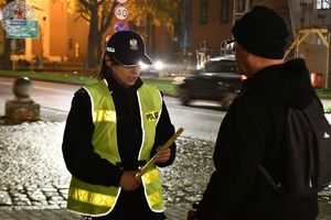 Zdjęcie kolorowe. Policjantka wręcza odblask