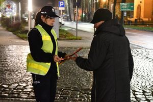 Zdjęcie kolorowe. Policjantka wręcza odblask