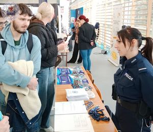 Zdjęcie kolorowe. Policjantka rozmawia z młodym chłopakiem