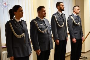 Zdjęcie kolorowe. Policjanci w mundurach galowych stoją w szeregu