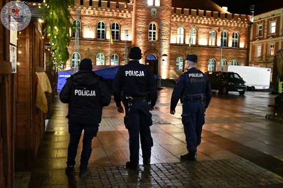 Zdjęcie kolorowe. Trzech policjantów patroluje ulicę