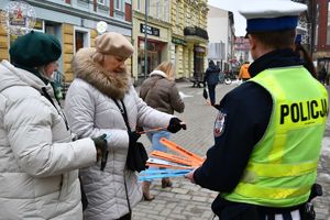 Zdjęcie kolorowe. Policjanci wręczają odblaski