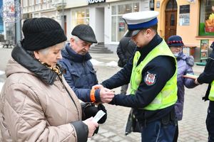 Zdjęcie kolorowe. Policjanci wręczają odblaski