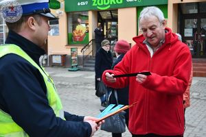 Zdjęcie kolorowe. Policjanci wręczają odblaski