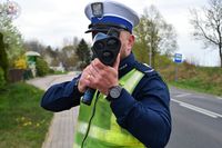 Zdjęcie kolorowe. Policjant ruchu drogowego z miernikiem prędkości