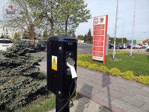 Zdjęcie kolorowe. Stacja ładująca przed budynkiem gminy