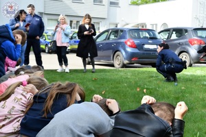 Zdjęcie kolorowe. Dzieci skulone ćwiczą bezpieczne zachowanie przed agresywnym psem.