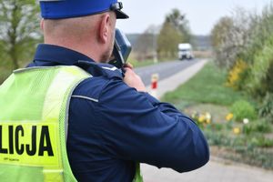 Zdjęcie kolorowe. Policjant mierzy prędkość