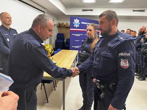 Zdjęcie kolorowe. Komendant gratuluje zespołowi który zajął 2 miejsce