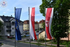 Zdjęcie kolorowe. Flagi powiatu Polski i Unii Europejskiej przed Komendą Powiatową Policji w Szczecinku