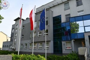 Zdjęcie kolorowe. Flagi powiatu Polski i Unii Europejskiej przed Komendą Powiatową Policji w Szczecinku