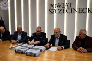 Zdjęcie kolorowe. Przy stole siedzą członkowie zarządu Starostwa Powiatowego w Szczecinku wraz z starostą i Komendantem Powiatowym Policji w Szczecinku