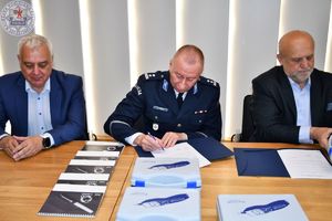 Zdjęcie kolorowe. Komendant podpisuje protokół przekazania
