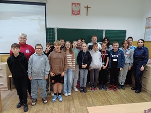 Zdjęcie kolorowe. Wspólne zdjęcie policjantki i przedstawicielki sanepidu z uczniami
