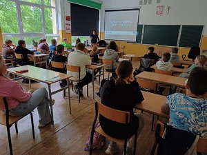 Zdjęcie kolorowe. Policjantka na spotkaniu z uczniami w klasie