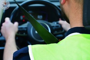Zdjęcie kolorowe. Zbliżenie pasów bezpieczeństwa zapiętych przez policjanta