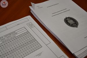 Zdjęcie kolorowe. Na stoliku leżą kwestionariusze pytań