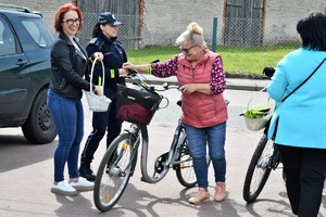Zdjęcia kolorowe. Uczestnicy rajdu na rowerach witani są przez organizatorów. Każdy uczestnik otrzymuje element odblaskowy.