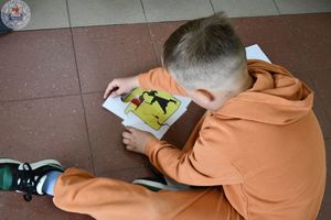 Zdjęcie kolorowe. Na podłodze dzieci układają puzzle ze znaku drogowego