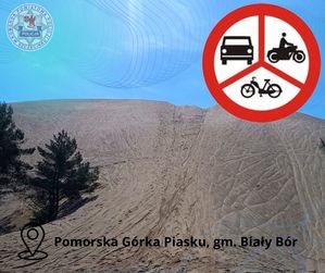 Zdjęcie kolorowe. Górka piachu na niej grafika znaku drogowego zakaz ruchu pojazdów silnikowych