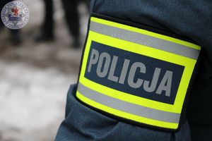 Zdjęcie kolorowe. Opaska z napisem policja umieszczona na przedramieniu