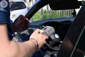 Zdjęcie kolorowe. Policjant trzyma urządzenie pomiarowo kontrolne