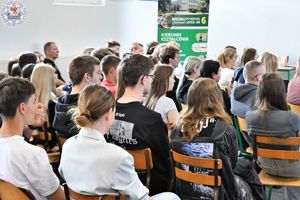 Zdjęcie kolorowe. Uczniowie siedzący na sali