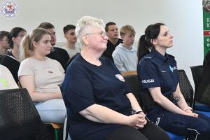 Zdjęcie kolorowe. Policjantka siedząca obok przedstawicielki sanepidu