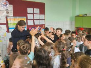 Zdjęcie kolorowe. Policjantka przybija piątkę z uczniami